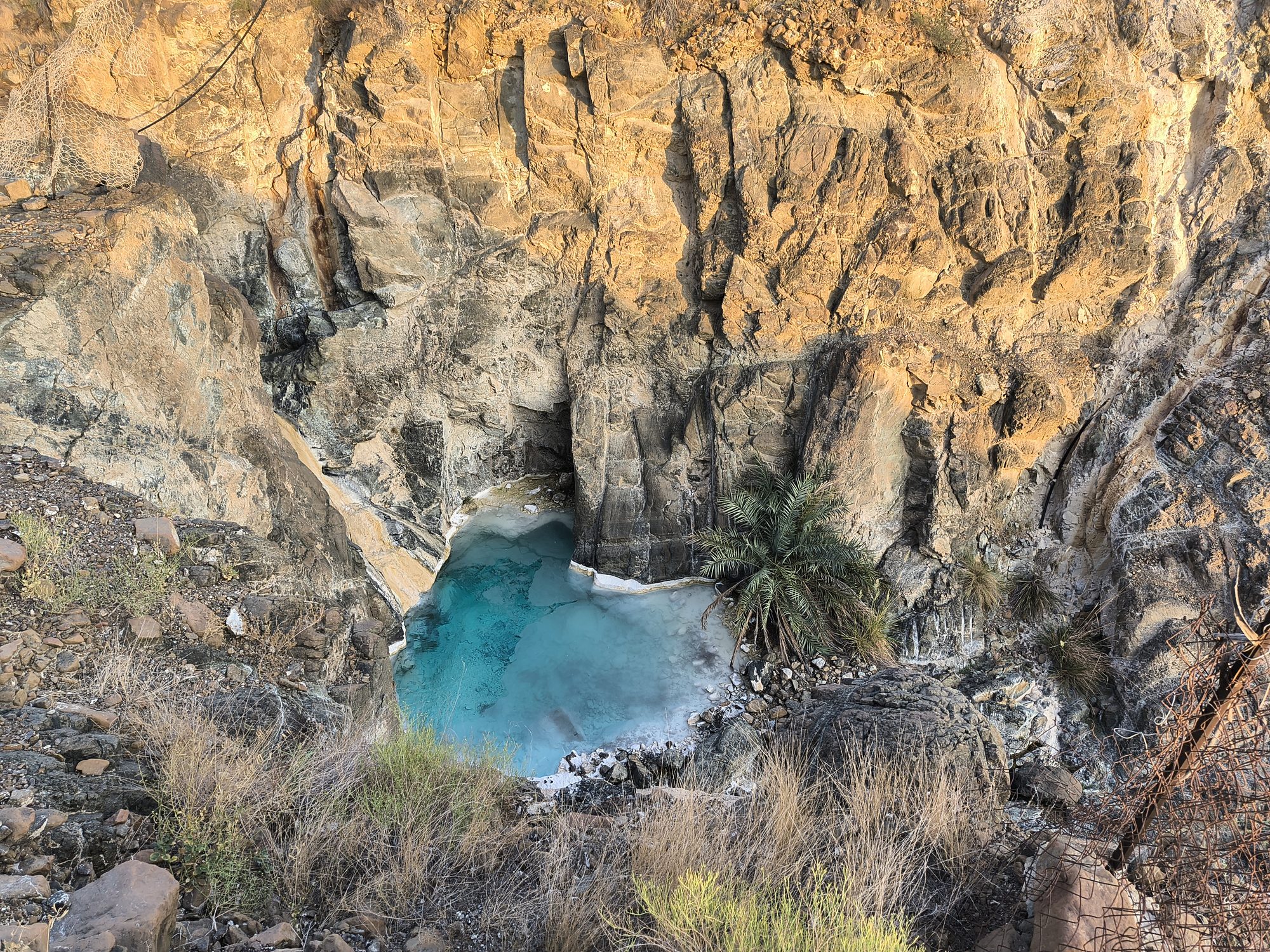 Turquoise pool below a rock wall